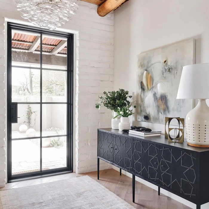 A white wall with a black and white sideboard with metal and glass patio door in Oklahoma City, OK